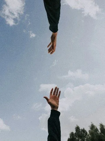 Deux mains tendues l’une vers l’autre sur fond de ciel
