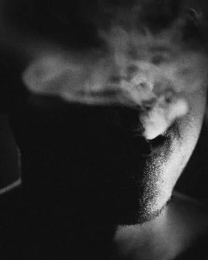 Visage partiellement visible dans l’ombre, expirant de la fumée