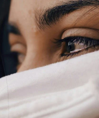 Gros plan sur le regard d’une personne, partiellement couvert par un tissu